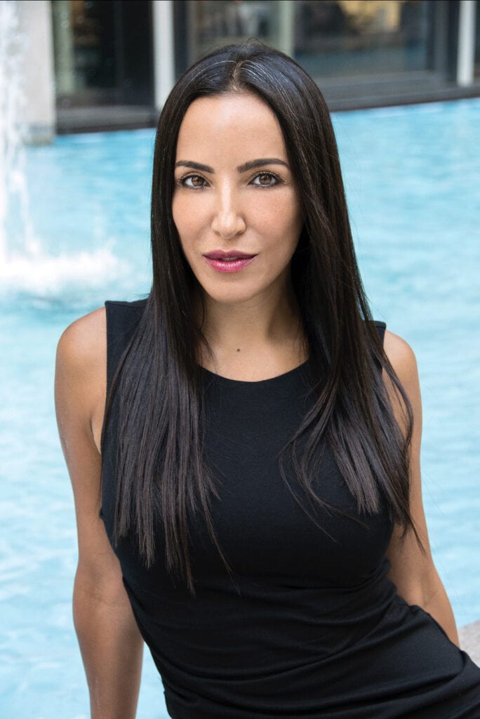 A woman in black shirt near water and fountain.